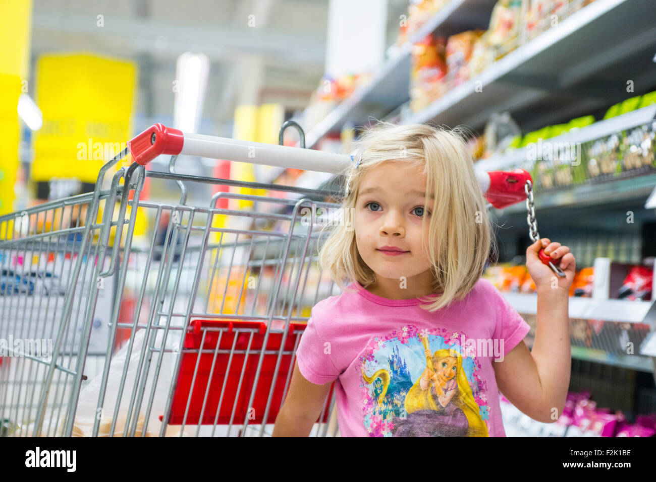 Kleines Kind blondes Mädchen Einkauf im Supermarkt, Wagen schieben, auf der Suche nach Süßigkeiten Stockfoto
