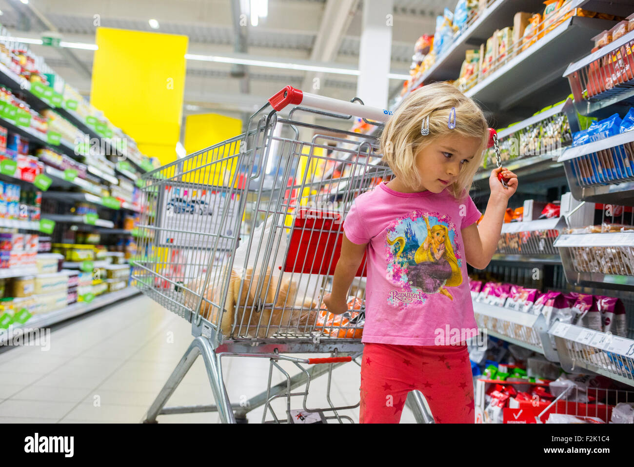 Kleines Kind blondes Mädchen Einkauf im Supermarkt, Wagen schieben, auf der Suche nach Süßigkeiten Stockfoto