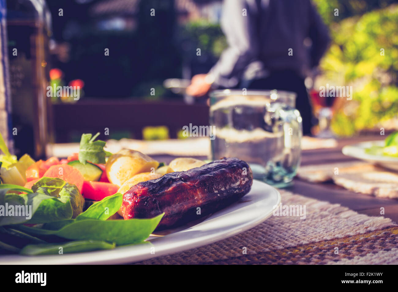 Wurst und Salat auf einem Teller außerhalb an einem Grill Stockfoto