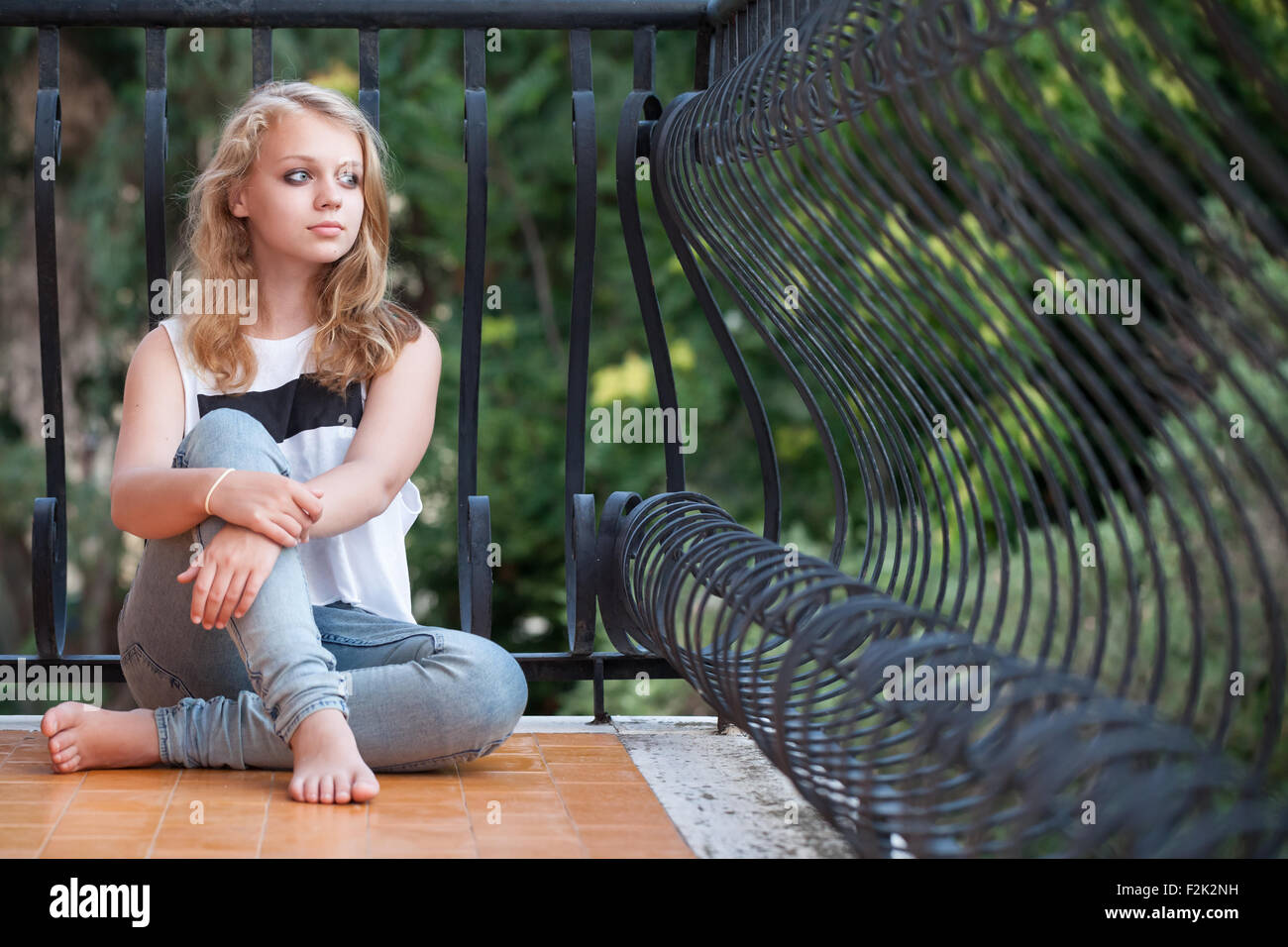 Schöne blondes kaukasische Mädchen sitzt auf Balkon, outdoor-Sommer-Porträt Stockfoto