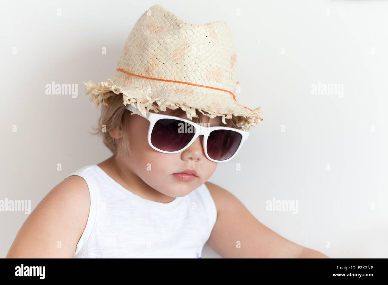 Süße kaukasische Mädchen in Stroh Hut und Sonnenbrille auf der weißen Wand Hintergrund Stockfoto