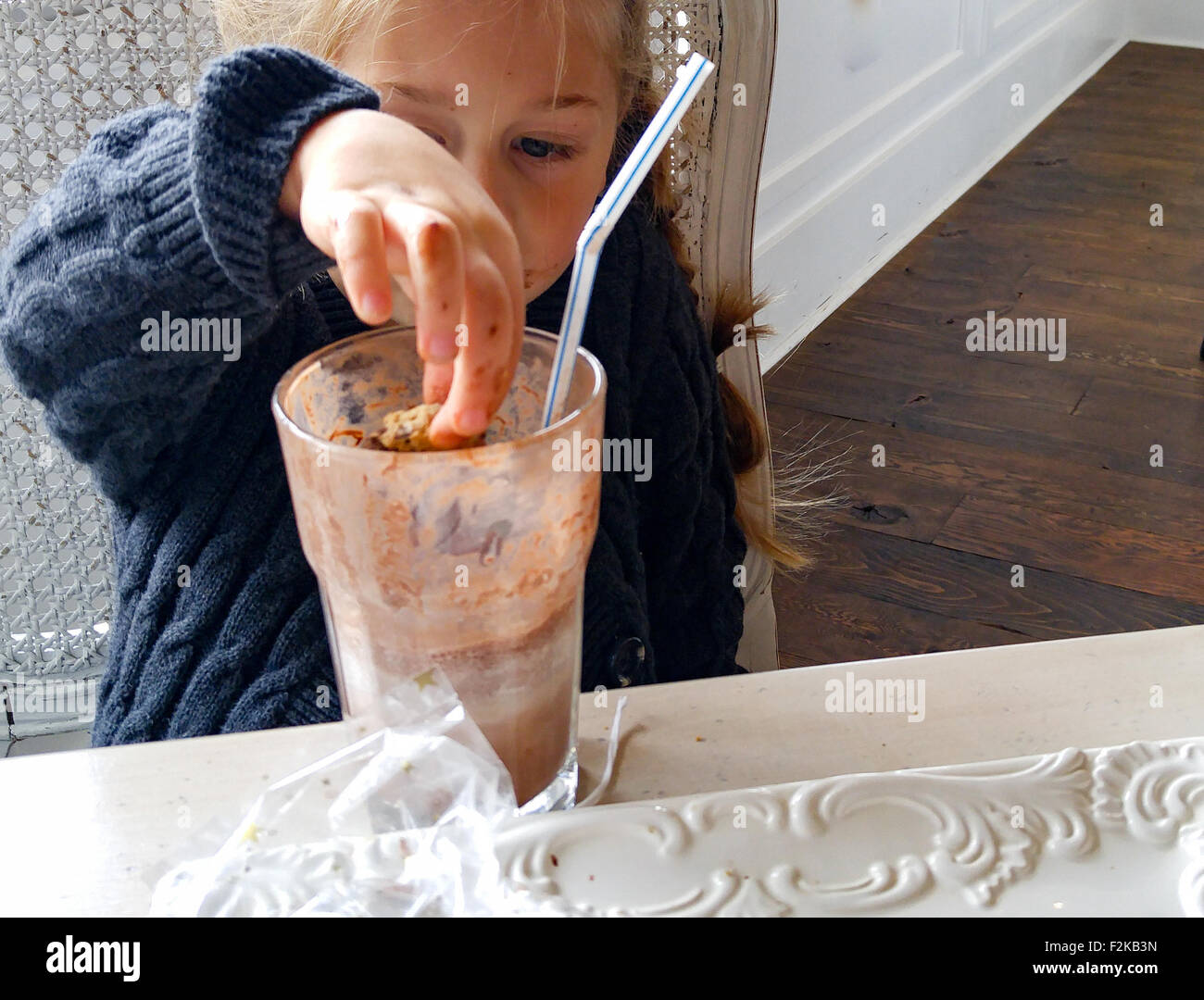 junges Mädchen taucht Cookie in einem Glas Milch Schokolade Stockfoto