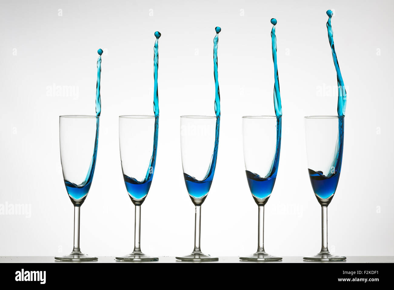 5 Sektgläser mit blau gefärbten Flüssigkeit spritzt aus.  High-Speed Flash-Fotografie Stockfoto