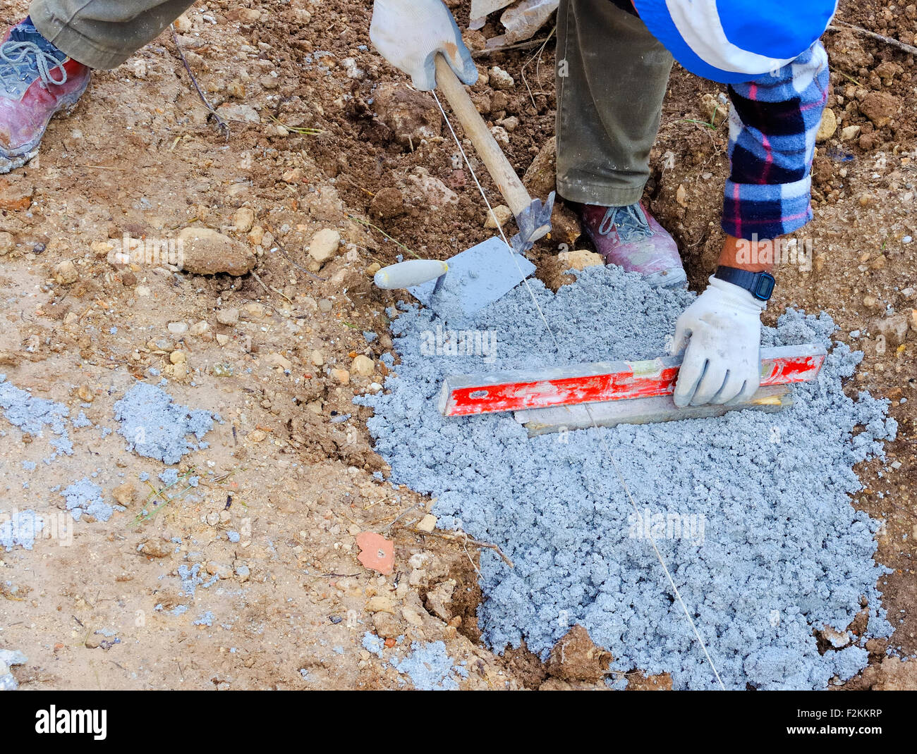 Arbeiter legt Plan ein Maß an die Stiftung des Gehwegs Stockfoto