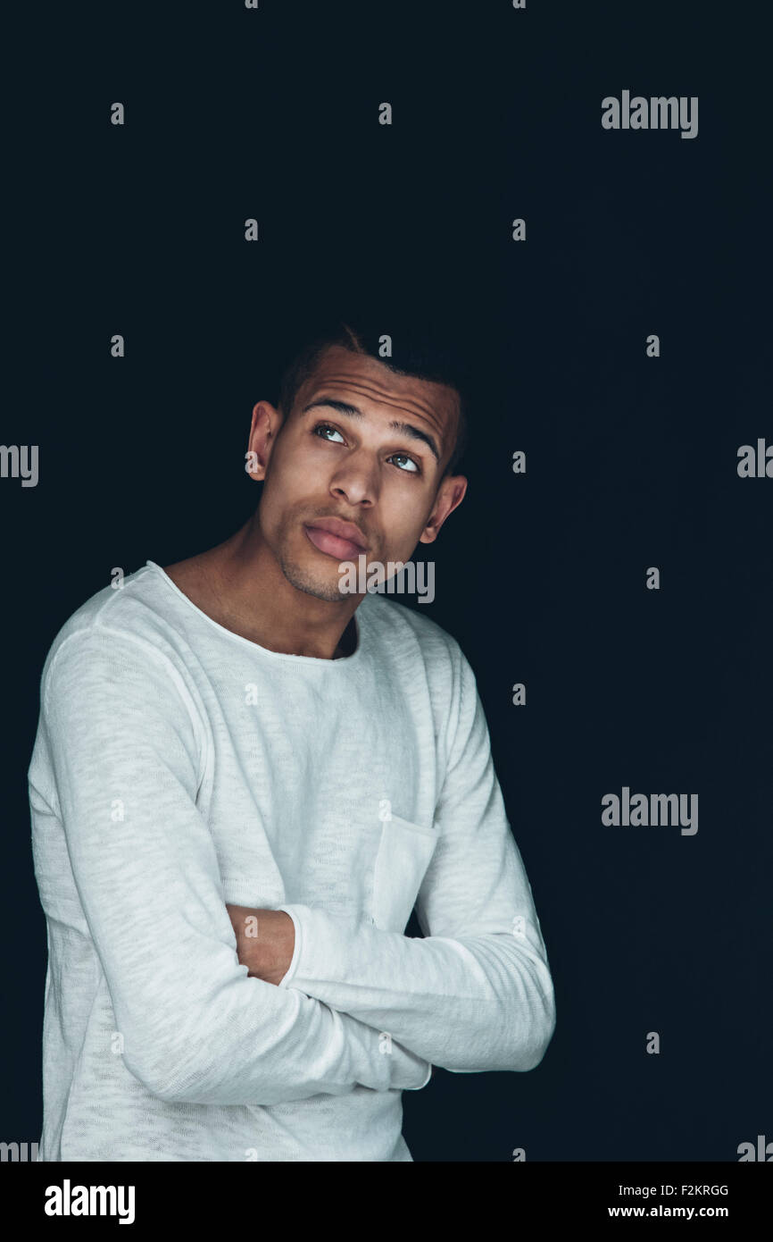 Porträt des jungen Mannes tragen weiße Sweatshirt vor schwarzem Hintergrund Stockfoto