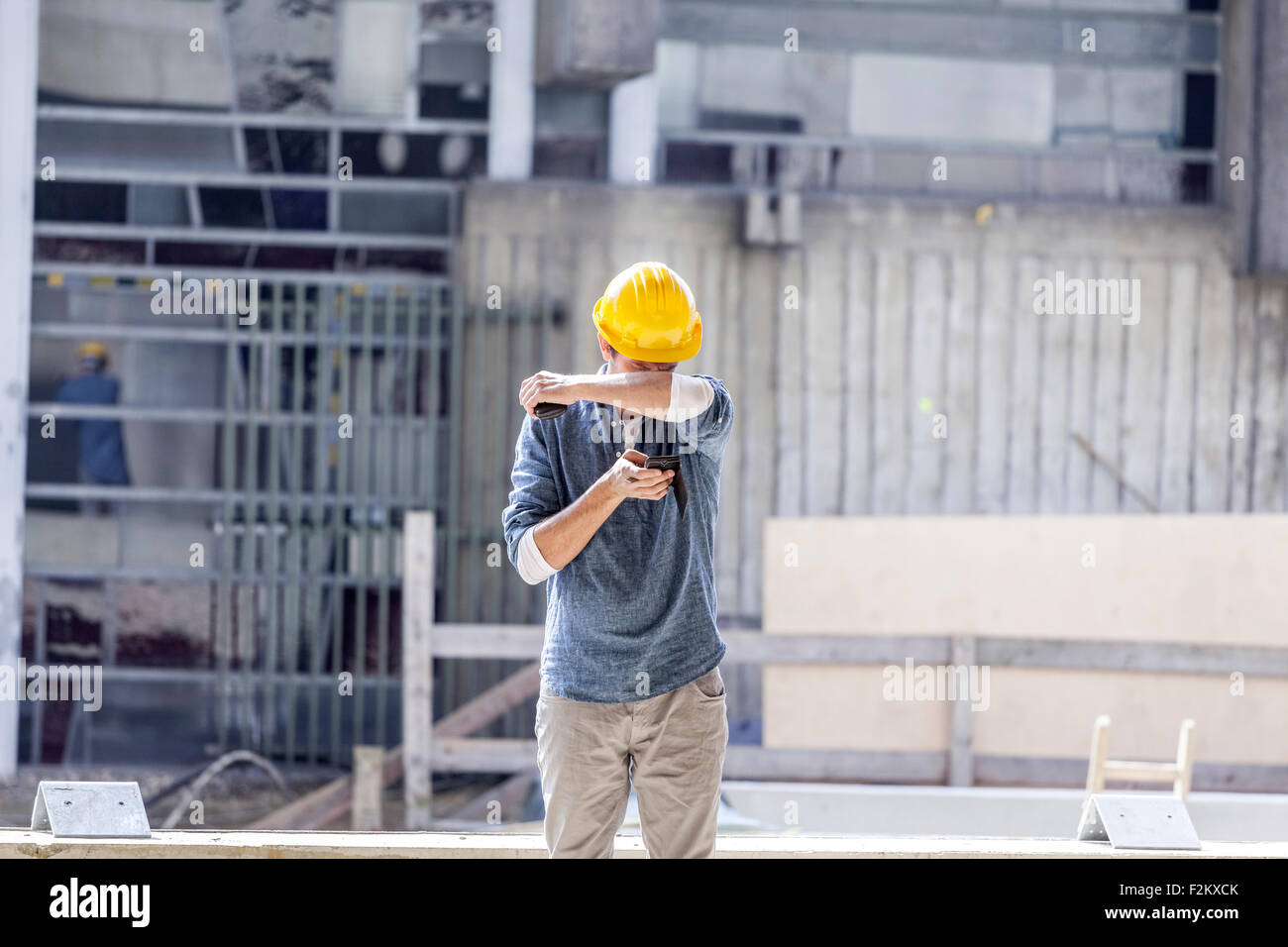 Mann mit Handy tragen Schutzhelm auf Baustelle Stockfoto