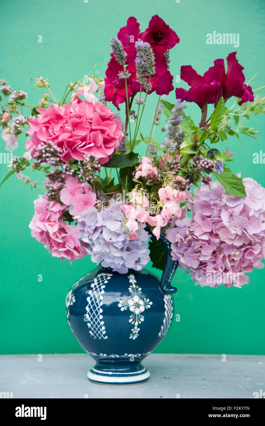 Blumenstrauß in einem Glas vor grünen Wand Stockfoto