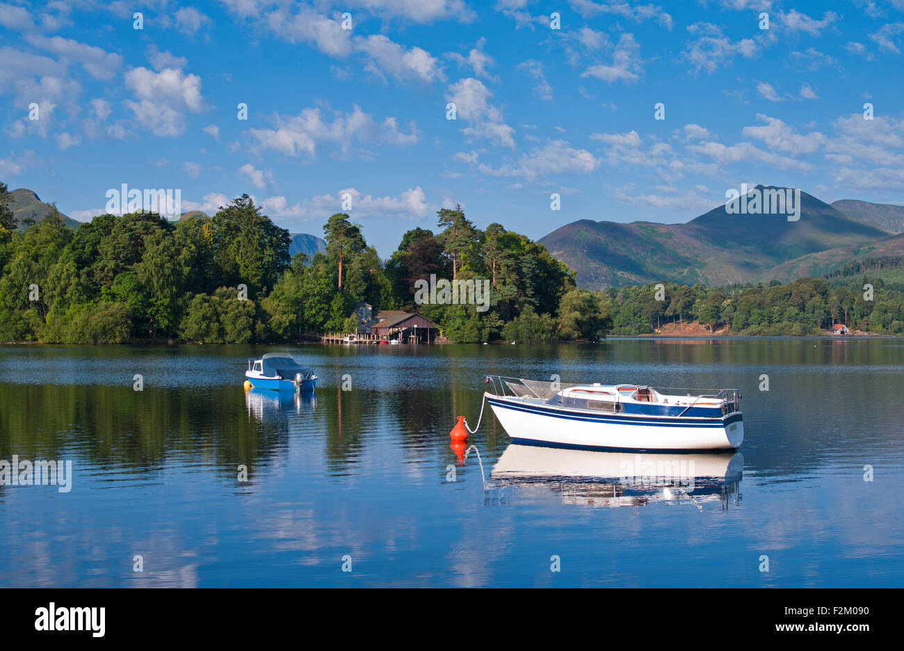 Blick auf kleine Boote vor Anker am Derwentwater bewaldeten Derwent Insel, steigt hinter Fjälls, ruhigen sonnigen Morgen, Cumbria UK Stockfoto