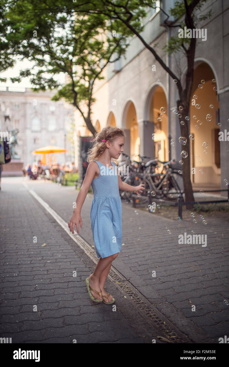 Deutschland, Berlin, kleine Mädchen tragen Ligh blue Sommer Kleid beobachten Seifenblasen Stockfoto
