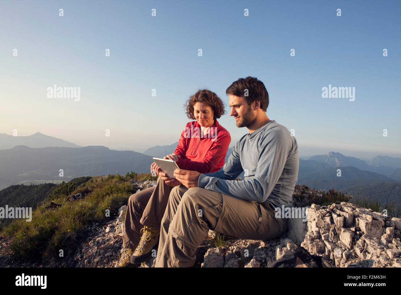 Österreich, Tirol, Unterberghorn, zwei Wanderer sitzen mit digital-Tablette in alpiner Landschaft Stockfoto