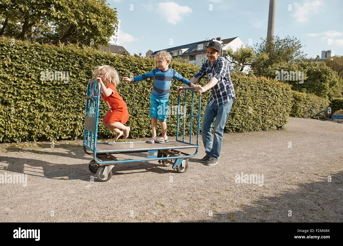 Vater treibt Handwagen mit zwei Kindern im Schrebergarten Bereich Stockfoto