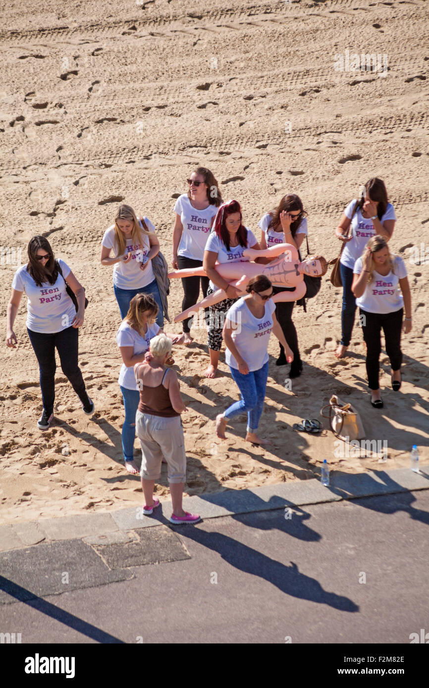 Junggesellinnenabschied mit Braut hält sprengen Puppe, den perfekten Mann, am Strand von Bournemouth im September Stockfoto