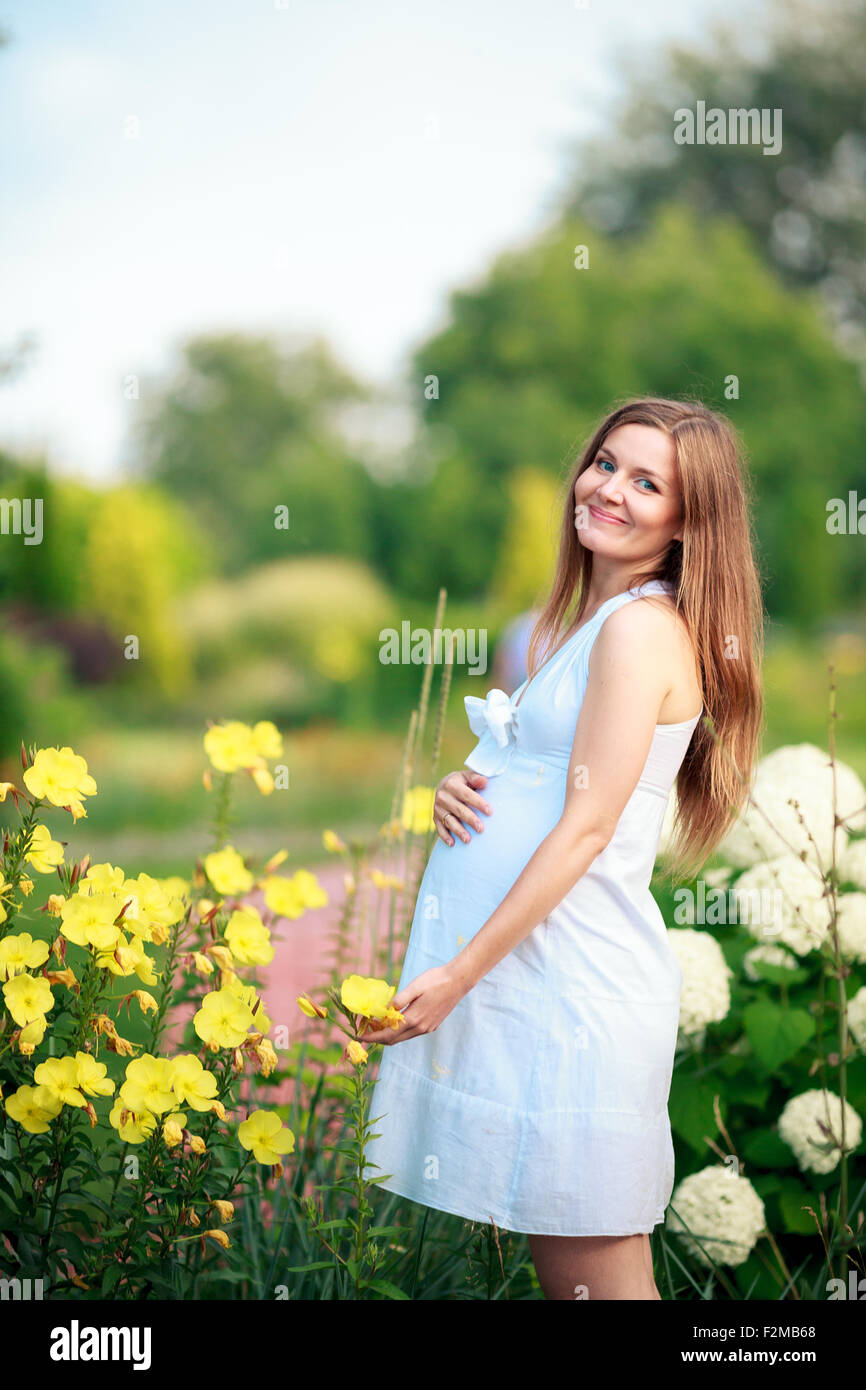 Schwangere Frau posiert in einem grünen Garten Stockfoto