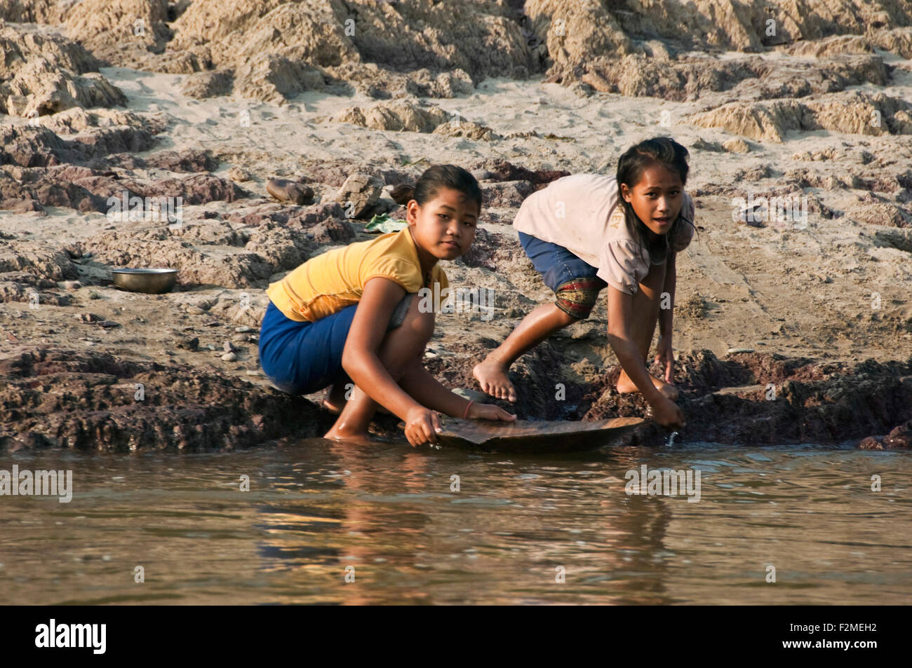 Horizontale Porträt von zwei jungen Mädchen Goldwaschen am Rande des Mekong-Flusses. Stockfoto