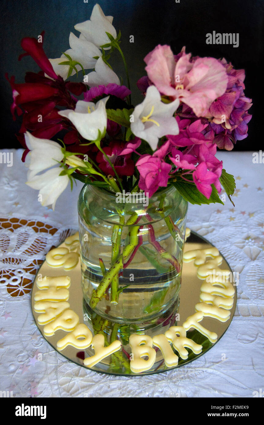 Vertikale Nahaufnahme einen Blumenstrauß mit handgefertigten 'Happy Birthday' Schokolade Stockfoto