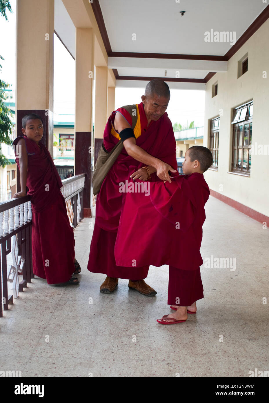 Ein junger Mönch erhält von seinem Lehrer ein wenig Hilfe mit seiner Robe.  Sera Jey Lobtra (Schule) Stockfoto
