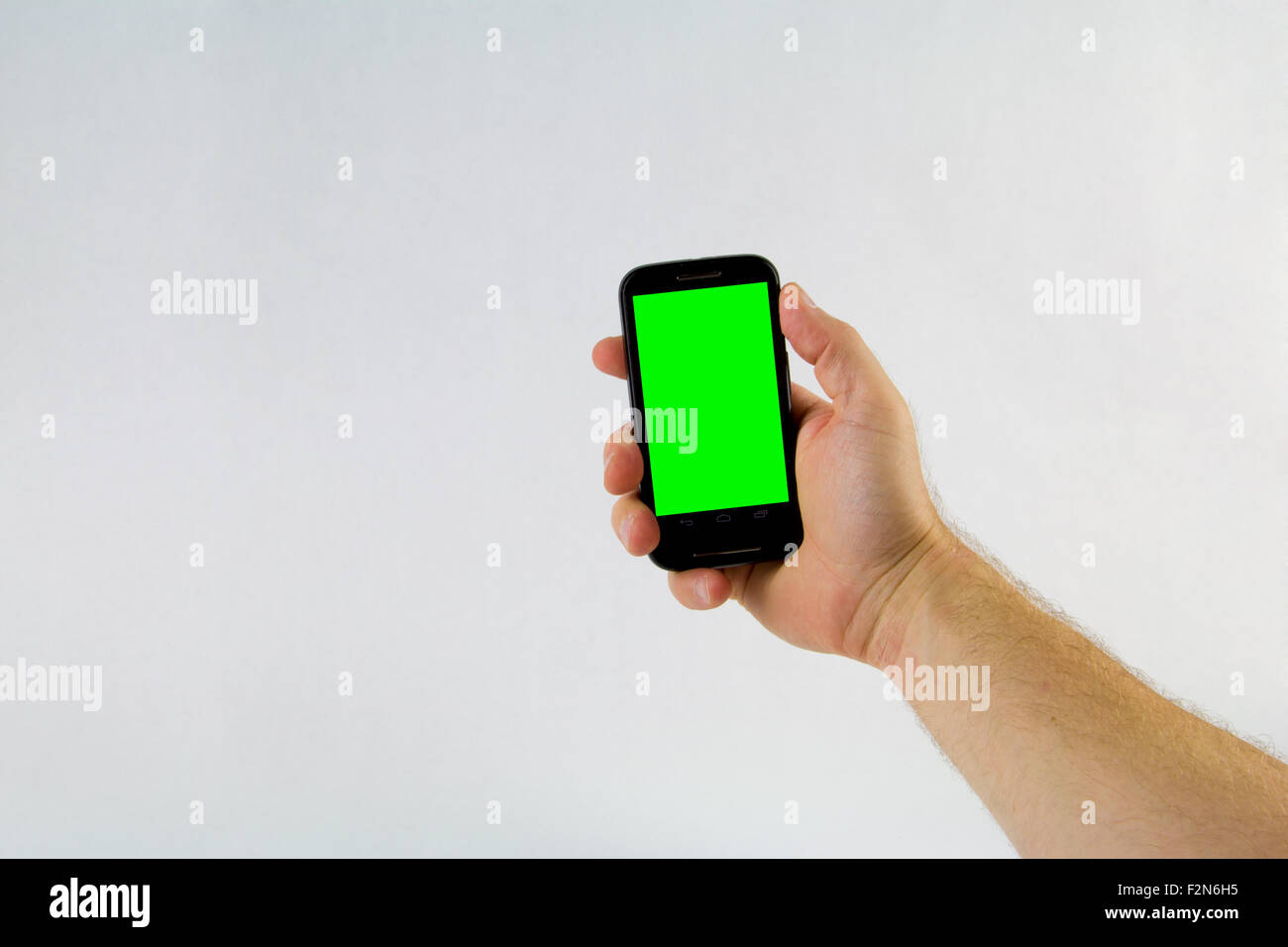Männliche Hand, die Handy auf weißem Hintergrund mit Greenscreen Stockfoto