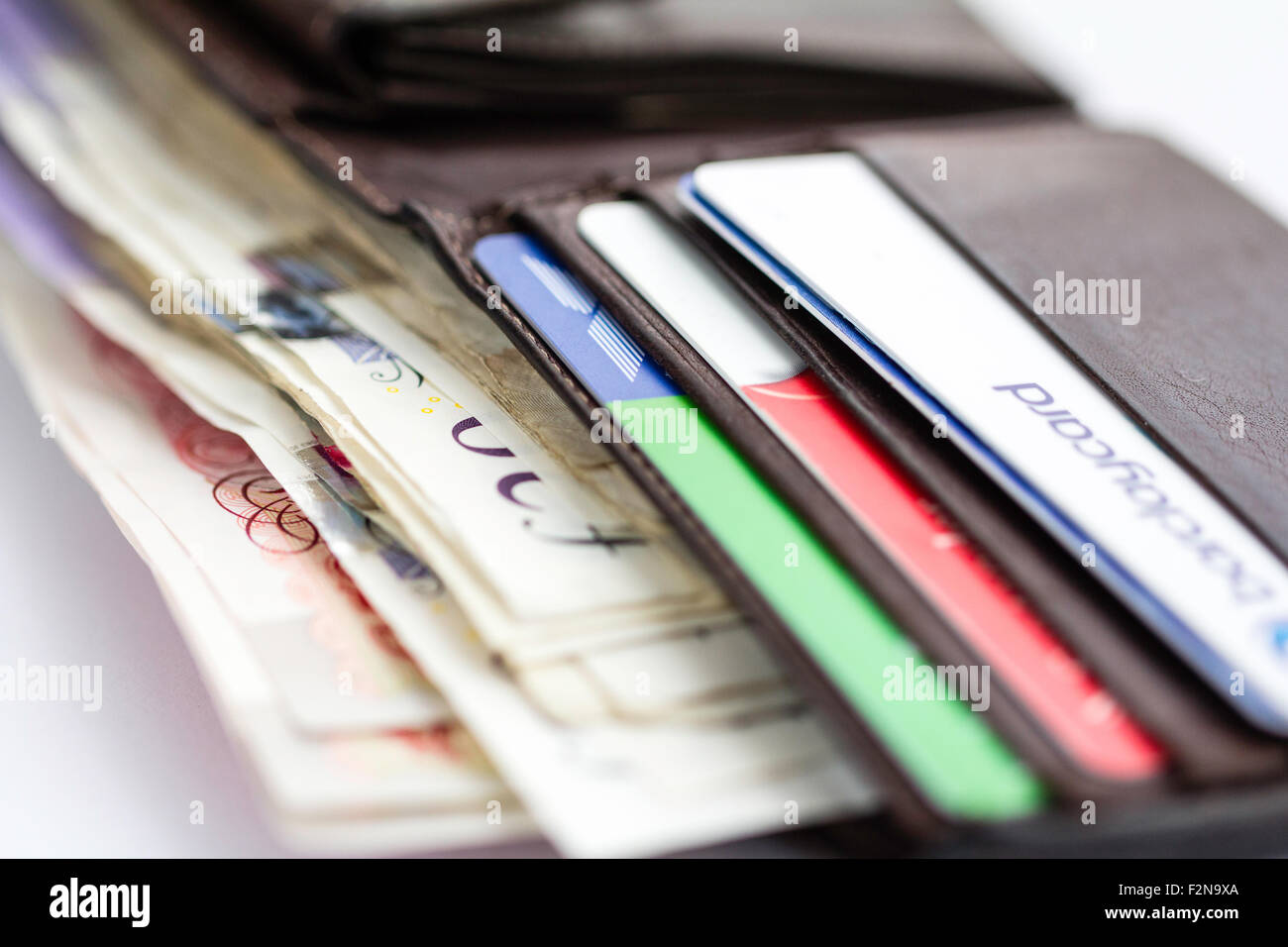 In der Nähe von offenen braunen Lederetui mit Kunststoff Kreditkarten und einige britische Pfund Banknoten im Hauptfach. Weißem Hintergrund. Stockfoto