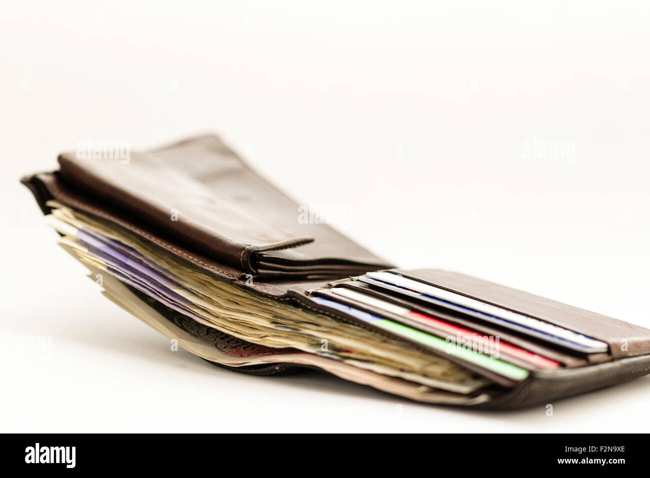 Dunkelbraun Leder Brieftasche Öffnen mit Banknoten und Kreditkarten auf weißem Hintergrund gepfercht. Scheint verloren oder wird unterbrochen. Stockfoto