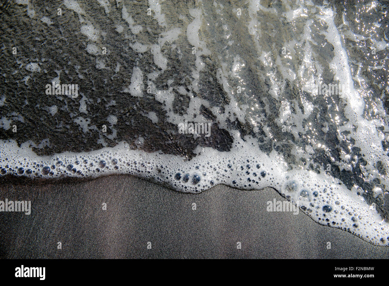 Dunklem Sand mit Wasser Welle Textur und Hintergrund Stockfoto