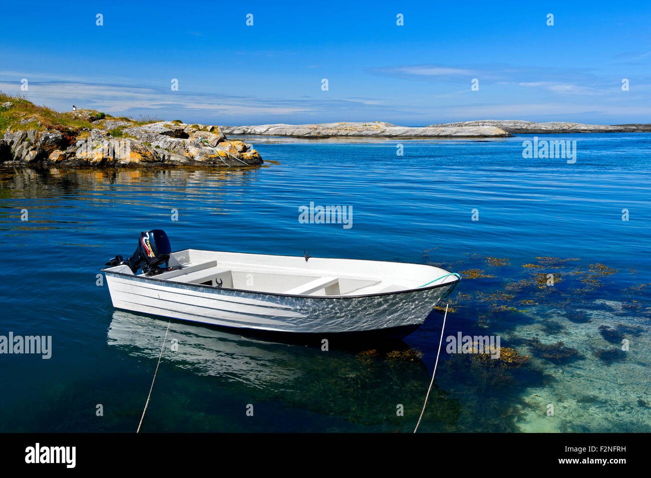 Weiße Motorboot verankert in einer Bucht in der felsigen Küstenlandschaft bei Bud, Gemeinde Fræna, Halbinsel Romsdal Møre Og Romsdal Stockfoto