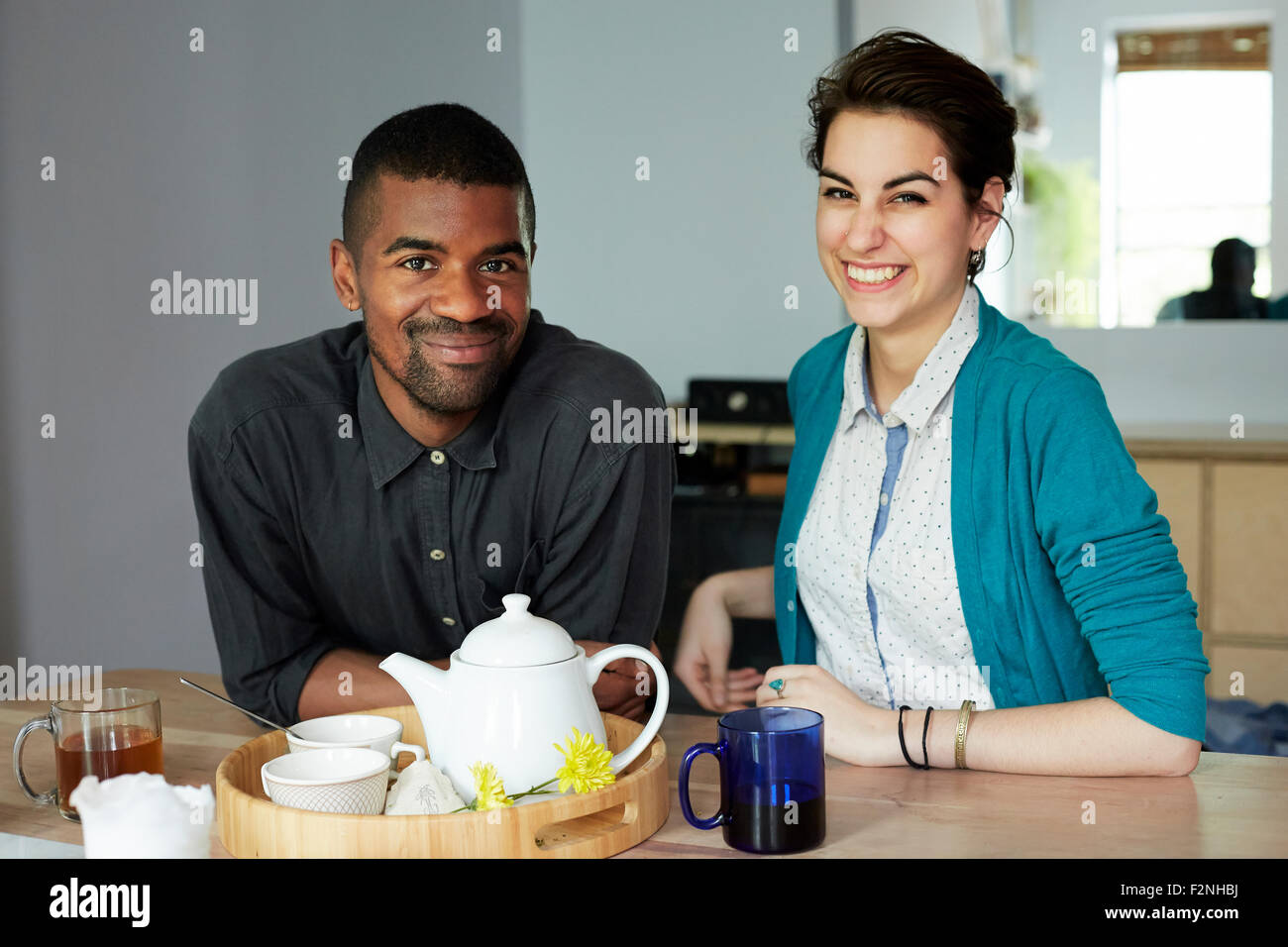 Paar lächelnd mit Tee am Tisch Stockfoto