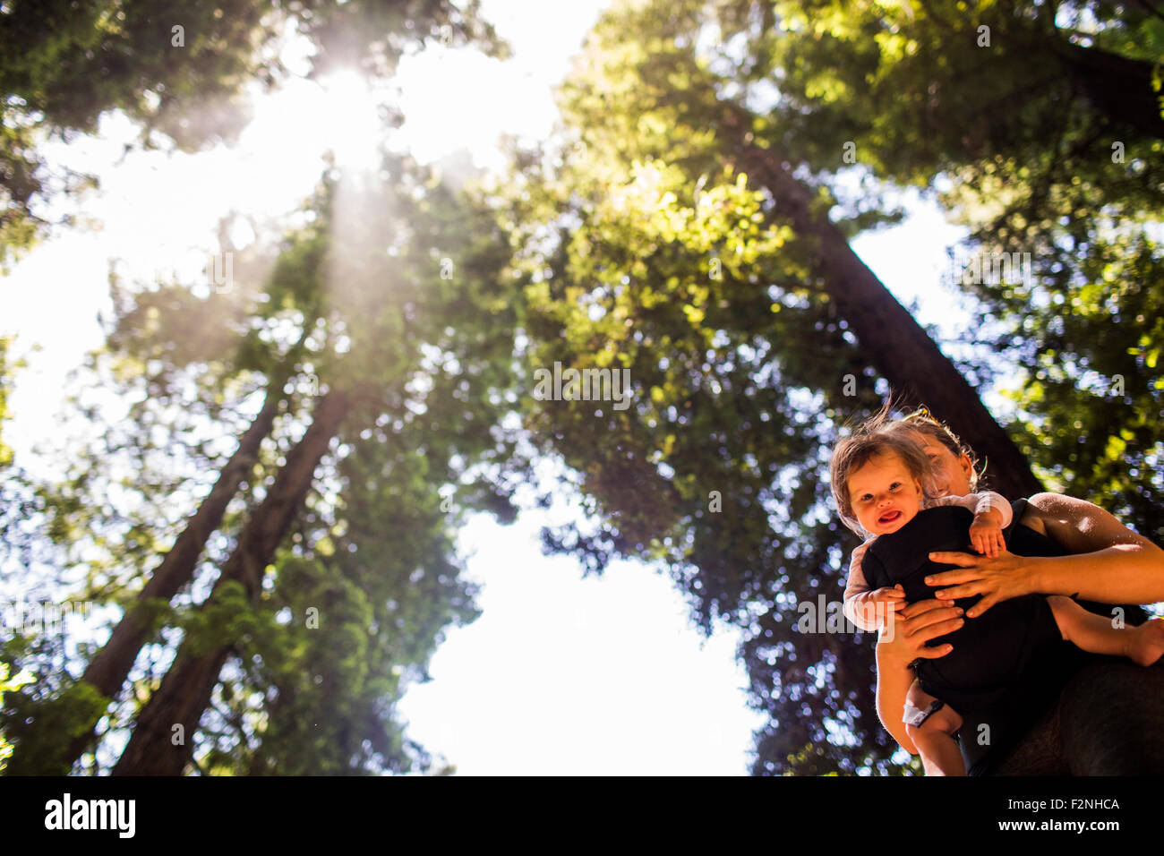 Kaukasische Mutter hält Babymädchen unter Bäumen Stockfoto