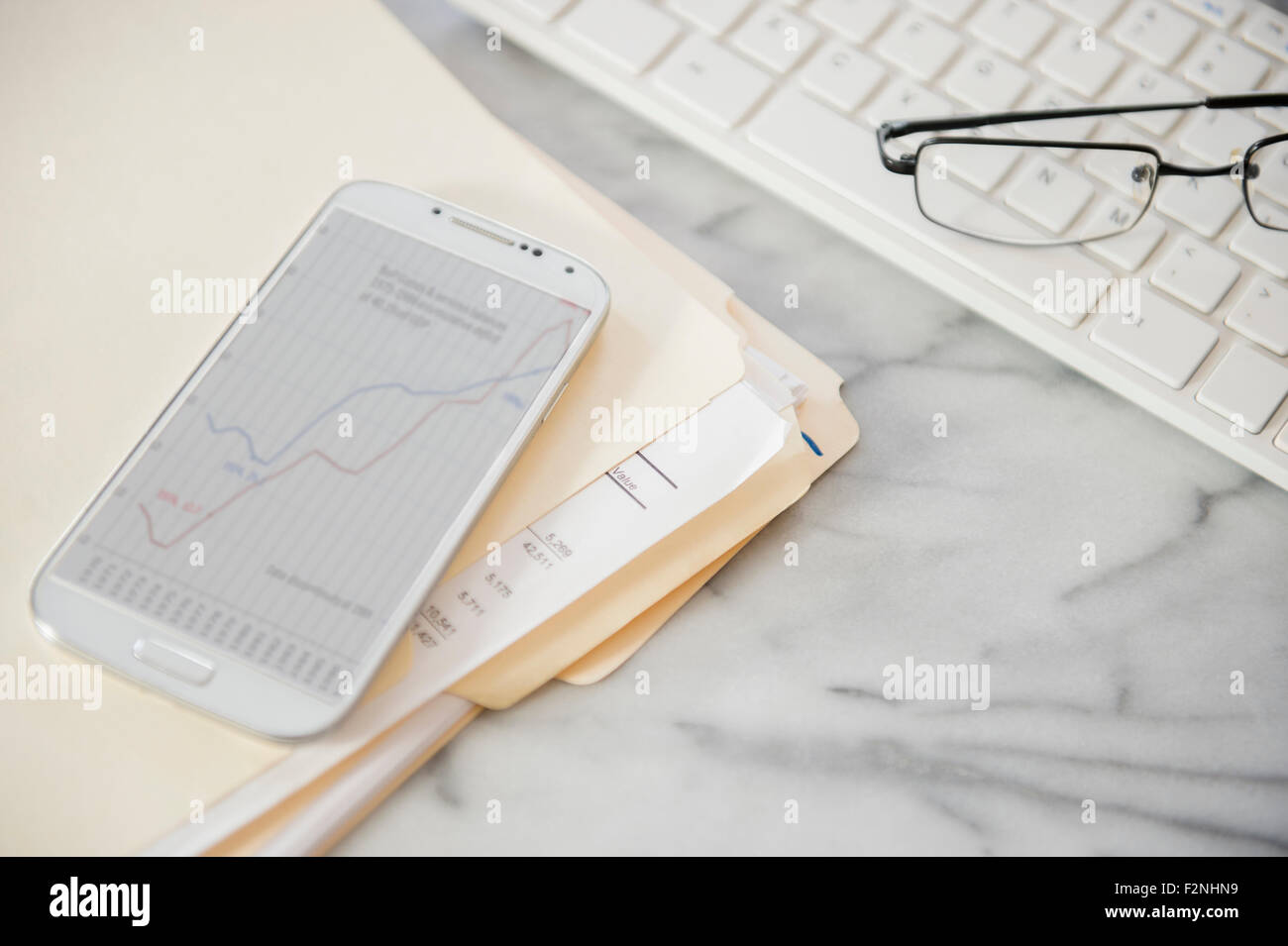 Nahaufnahme von Computer-Tastatur, Dateien, Handy und Brillen auf Schreibtisch Stockfoto