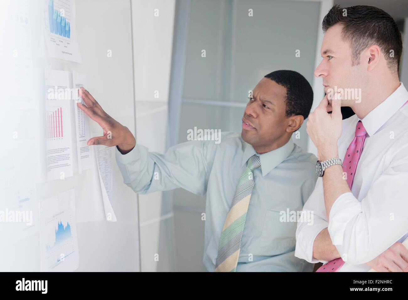 Geschäftsleute, die Charts im Büro an der Wand zu prüfen Stockfoto