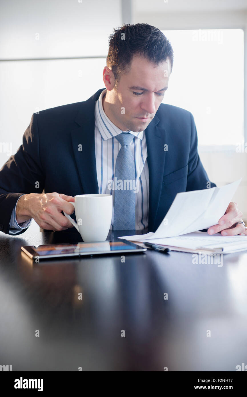 Geschäftsmann, trinken Kaffee und Papierkram zu lesen Stockfoto