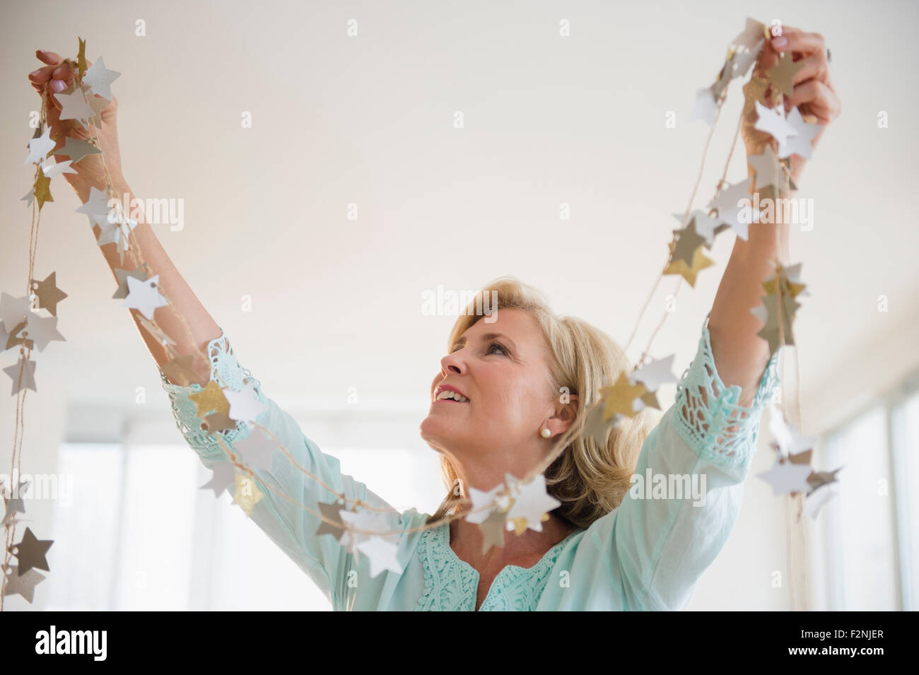 Kaukasische Frau mit Girlande im Wohnzimmer Dekoration Stockfoto