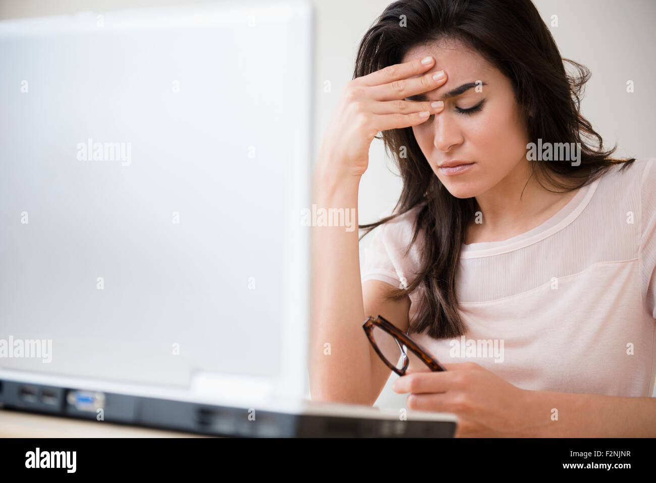 Betonte Frau reiben ihre Stirn an laptop Stockfoto
