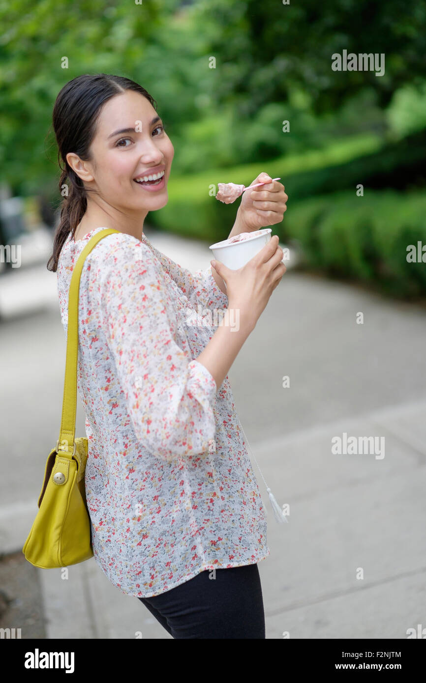 Hispanic Frau gefrorenen Joghurt auf Bürgersteig der Stadt Essen Stockfoto