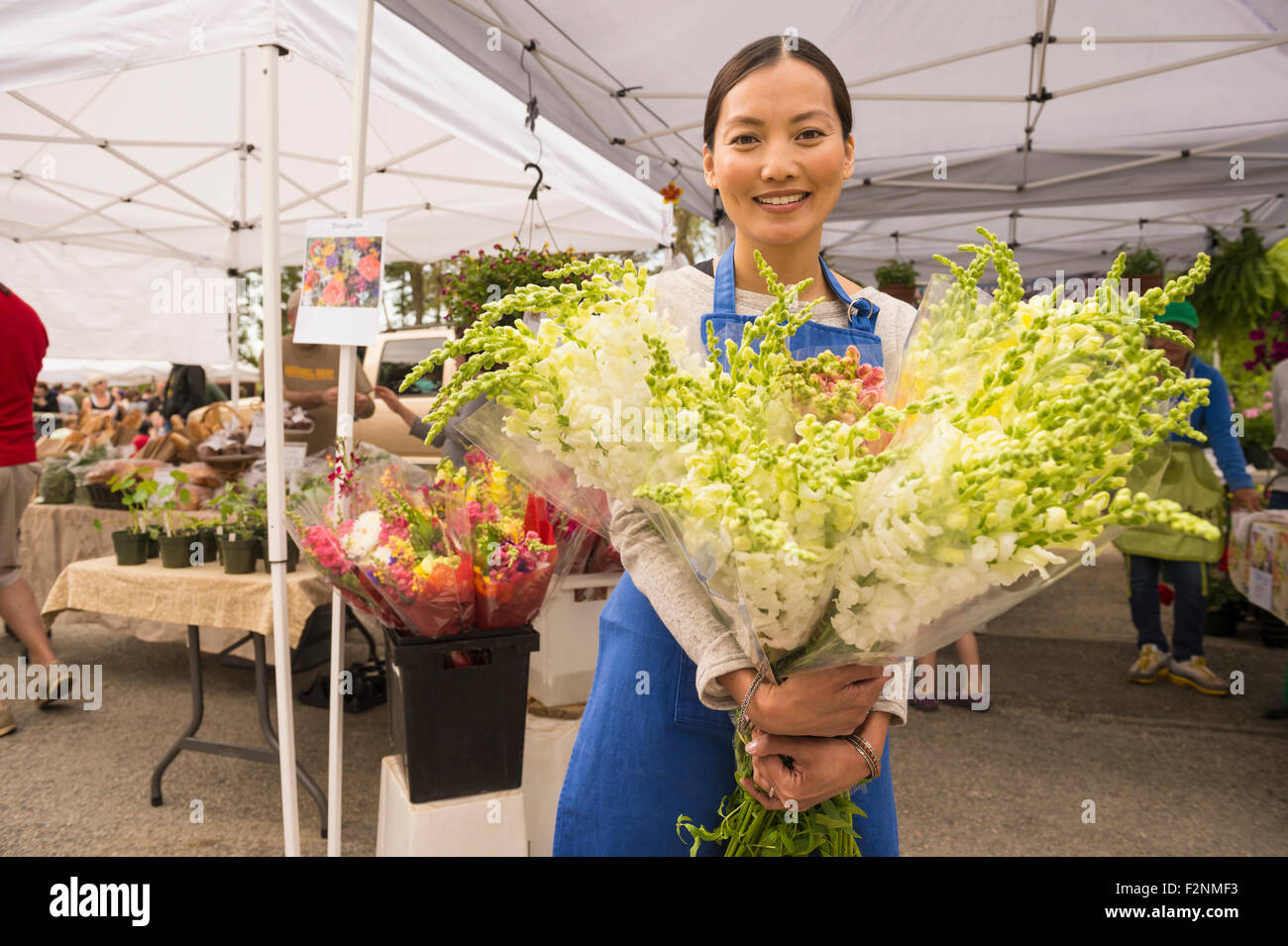 Asiatische Angestellte halten frische Blumen am Bauernmarkt Stockfoto