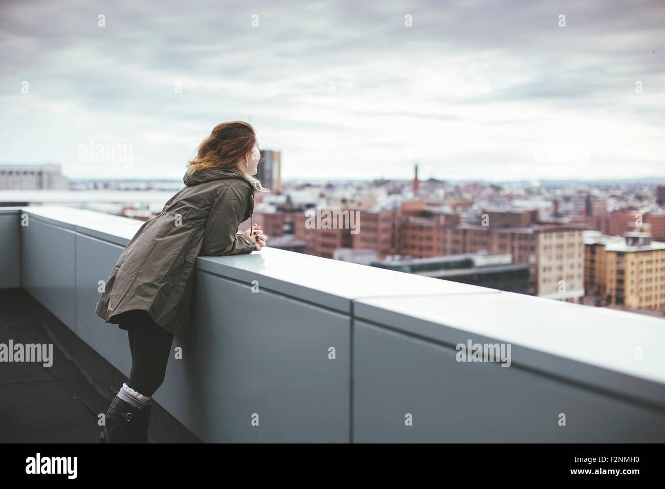 Kaukasische Frau auf städtischen Dach bewundern Stadtbild Stockfoto