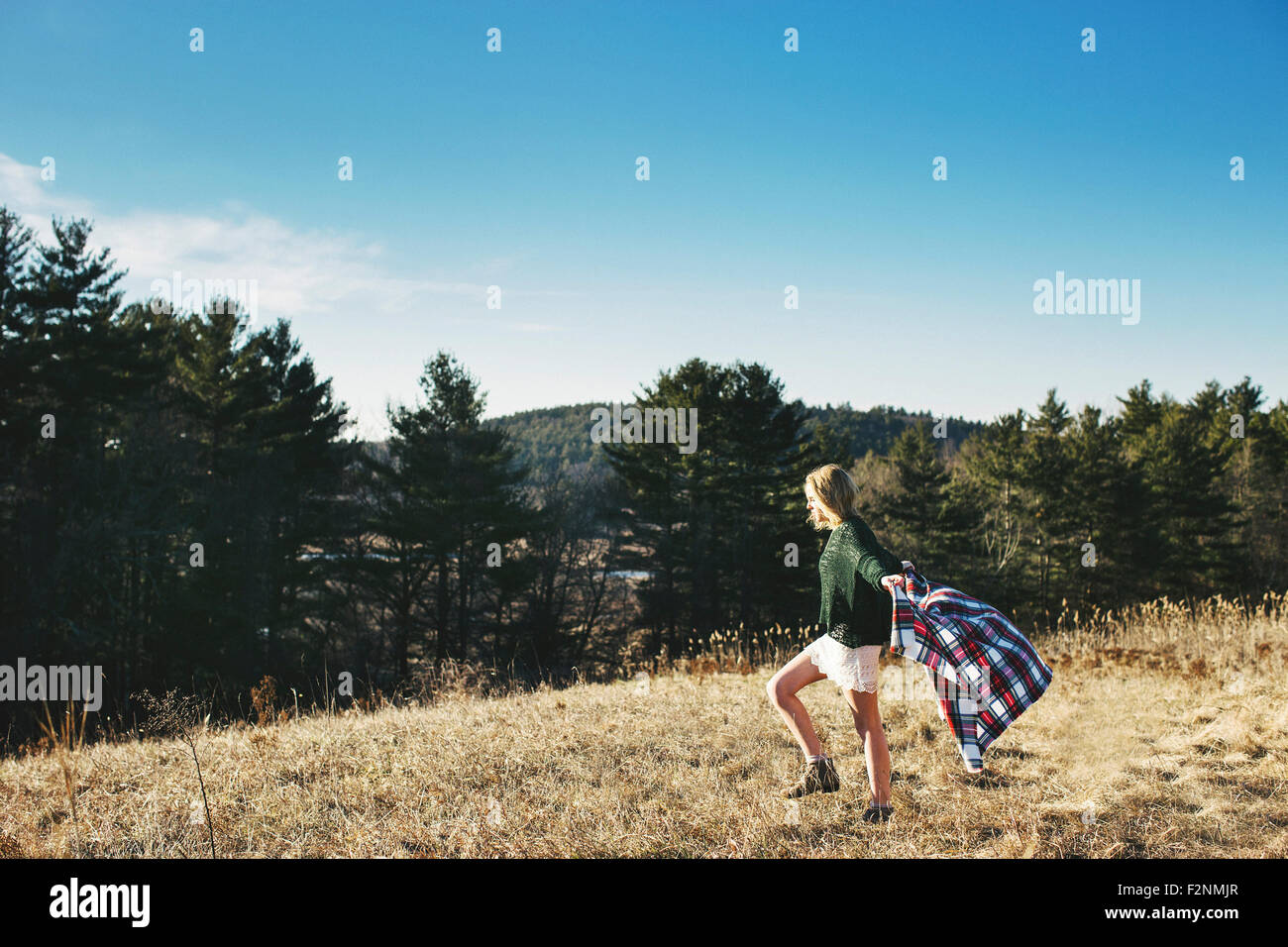 Kaukasische Frau spielt mit Schal auf ländlichen Hügel Stockfoto