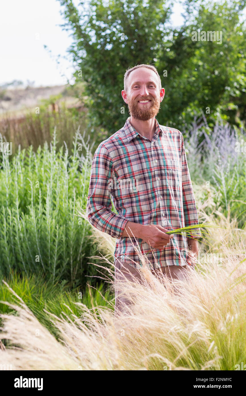 Kaukasischen Mann hohe Pflanzen im Garten zu bewundern Stockfoto