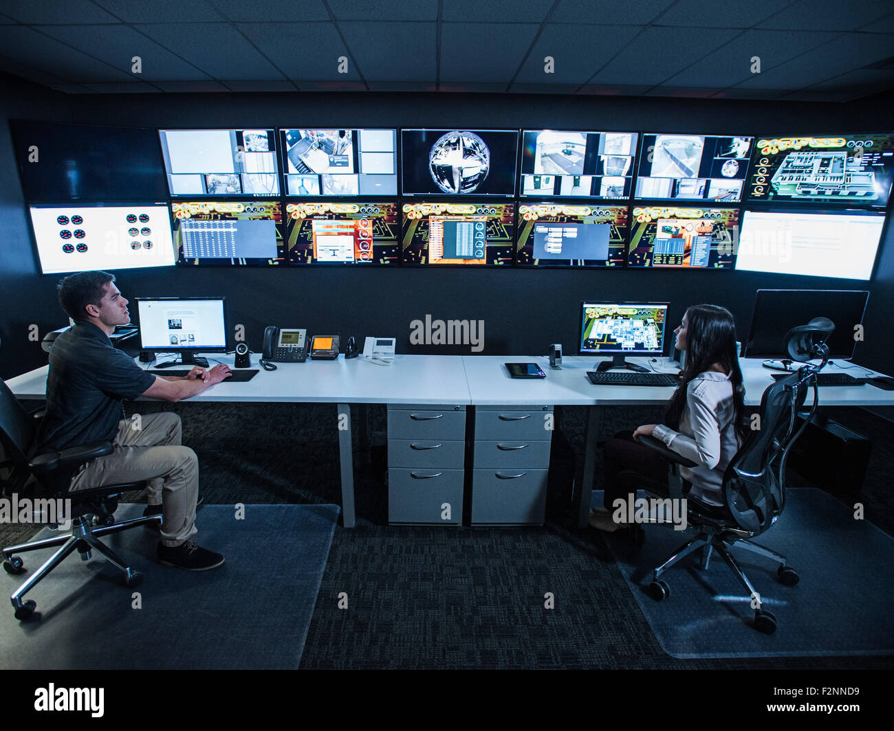 Wachleute beobachten Monitore im Kontrollraum Stockfoto