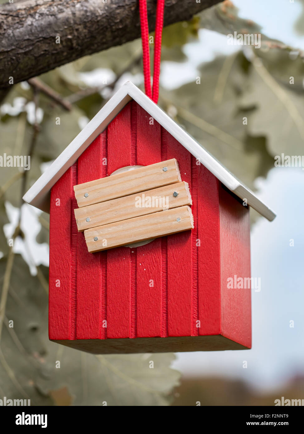 Hölzerne rote Vogelhaus hängend auf Ast mit Eintrag Loch mit Brettern abgedeckt Stockfoto