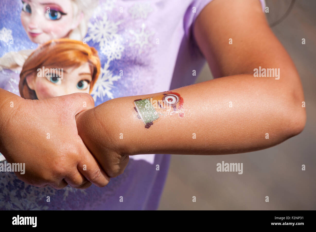 Junges Mädchen mit Minion temporäre Tattoo Transfer am Arm und tragen Frozen top Stockfoto