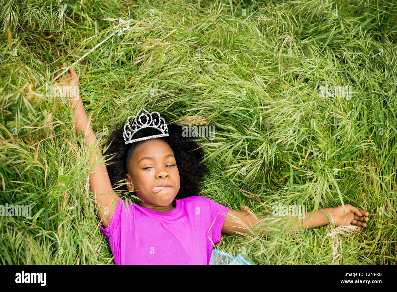 Schwarze Mädchen in Prinzessin Diadem Verlegung in Rasen Stockfoto