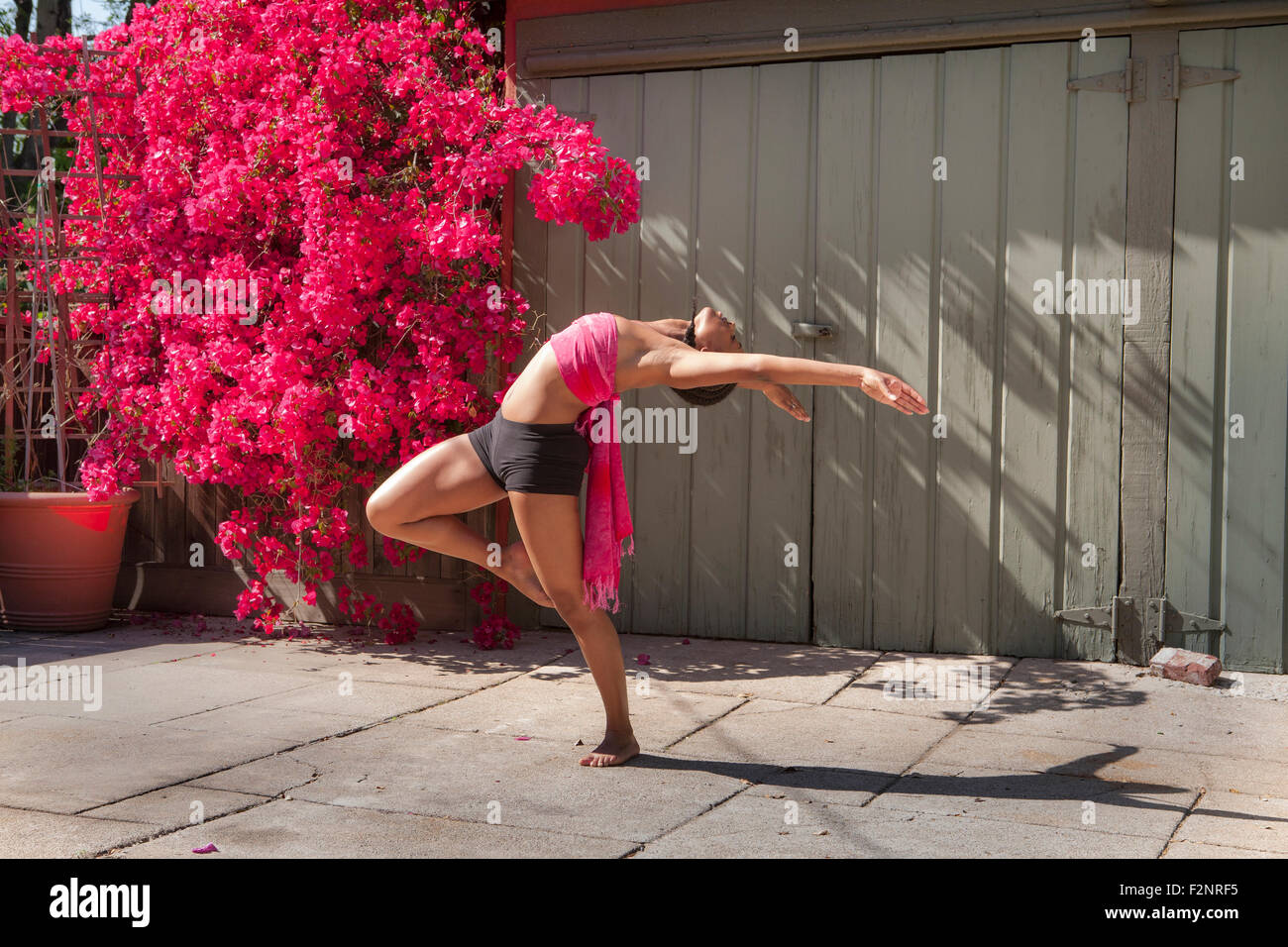 Frau praktizieren Yoga in der Nähe von Blumen und Zaun Stockfoto