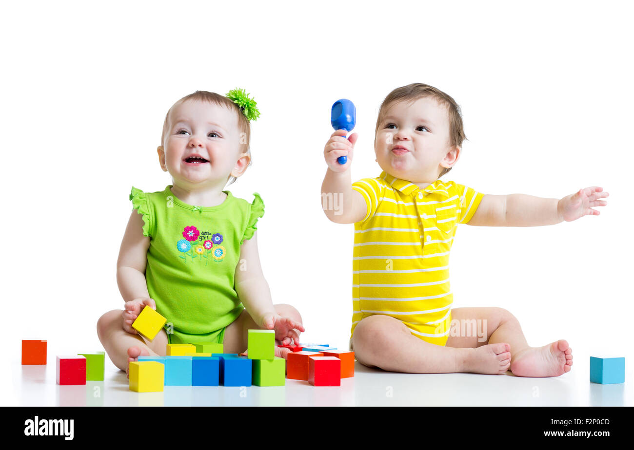 Zwei entzückende Babys spielen mit Spielzeug. Kleinkinder-Mädchen und jungen am Boden. Isoliert auf weißem Hintergrund. Stockfoto