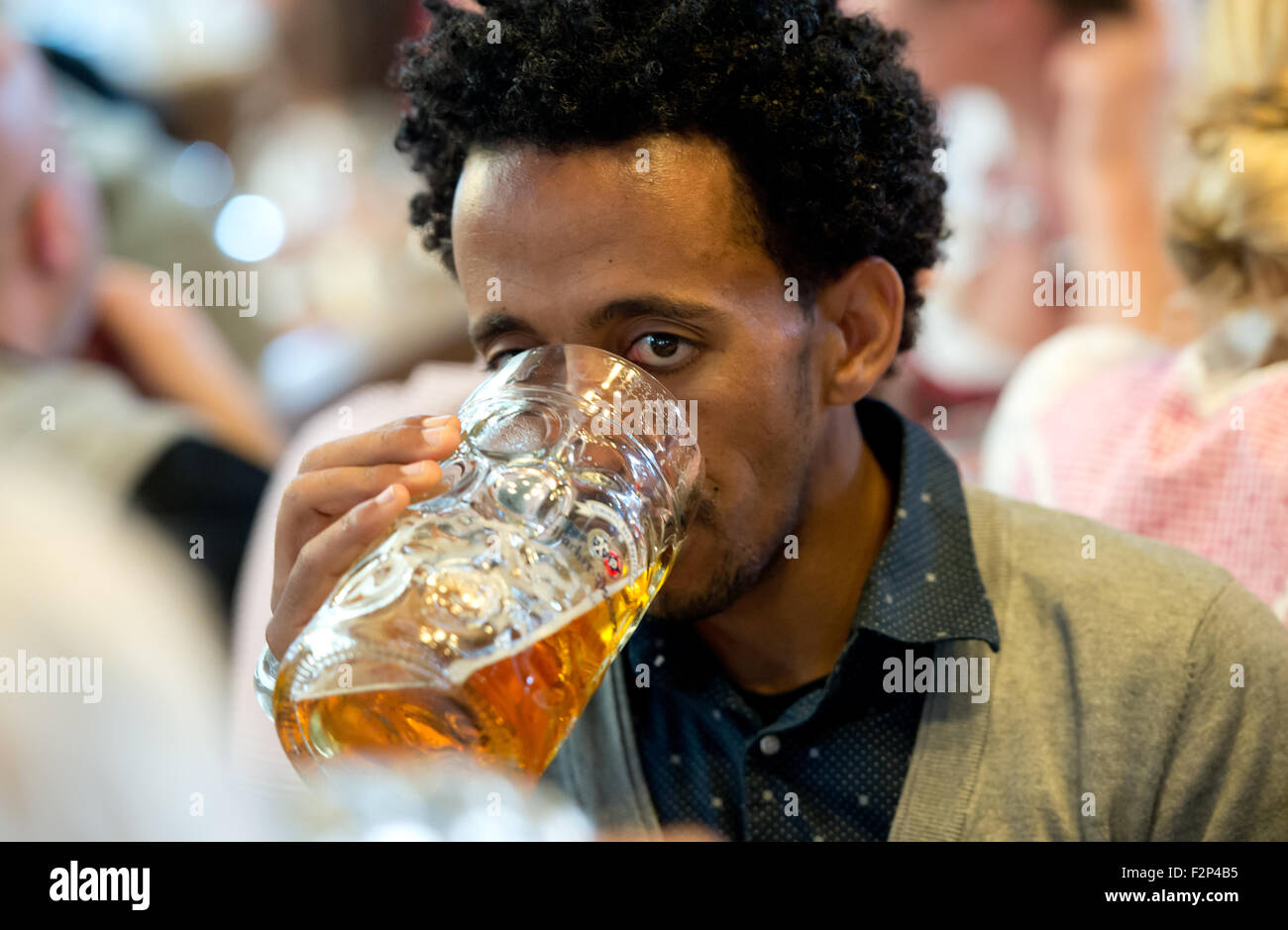 Ein Asylbewerber aus Eritrea genießt die Erfrischungen Sonntag an einem der berühmten Bierzelten des Oktoberfestes. Freiwillige in München nahm eine Gruppe von Asylsuchenden, die weltweit größte Messe, die bekannt ist für sein Bier, bayerische Mode und Spaß. DPA/SVEN HOPPE Stockfoto