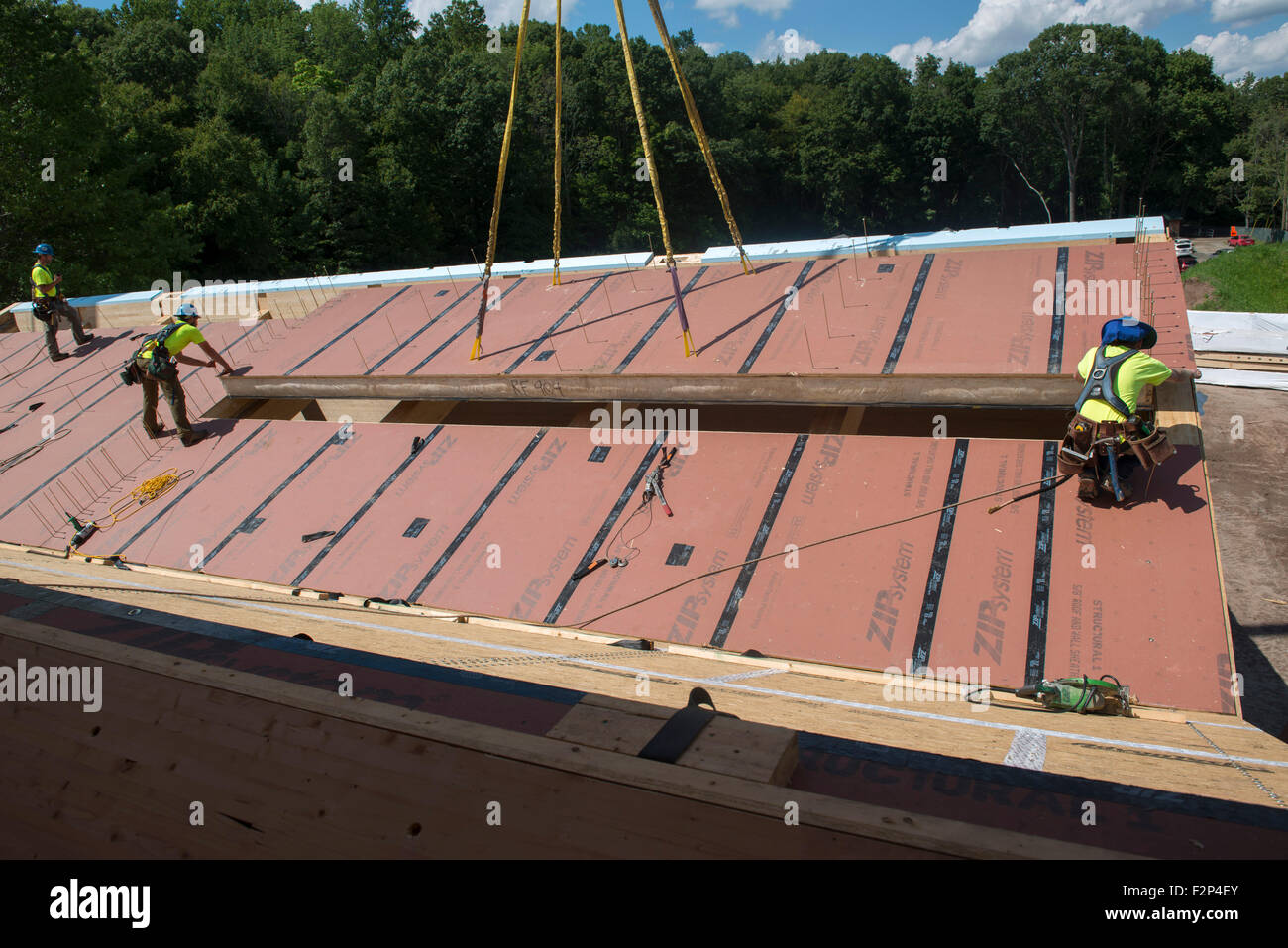 Bauarbeiter installieren Dachplatten auf Leed Platin Common Ground High School Gebäude. Stockfoto