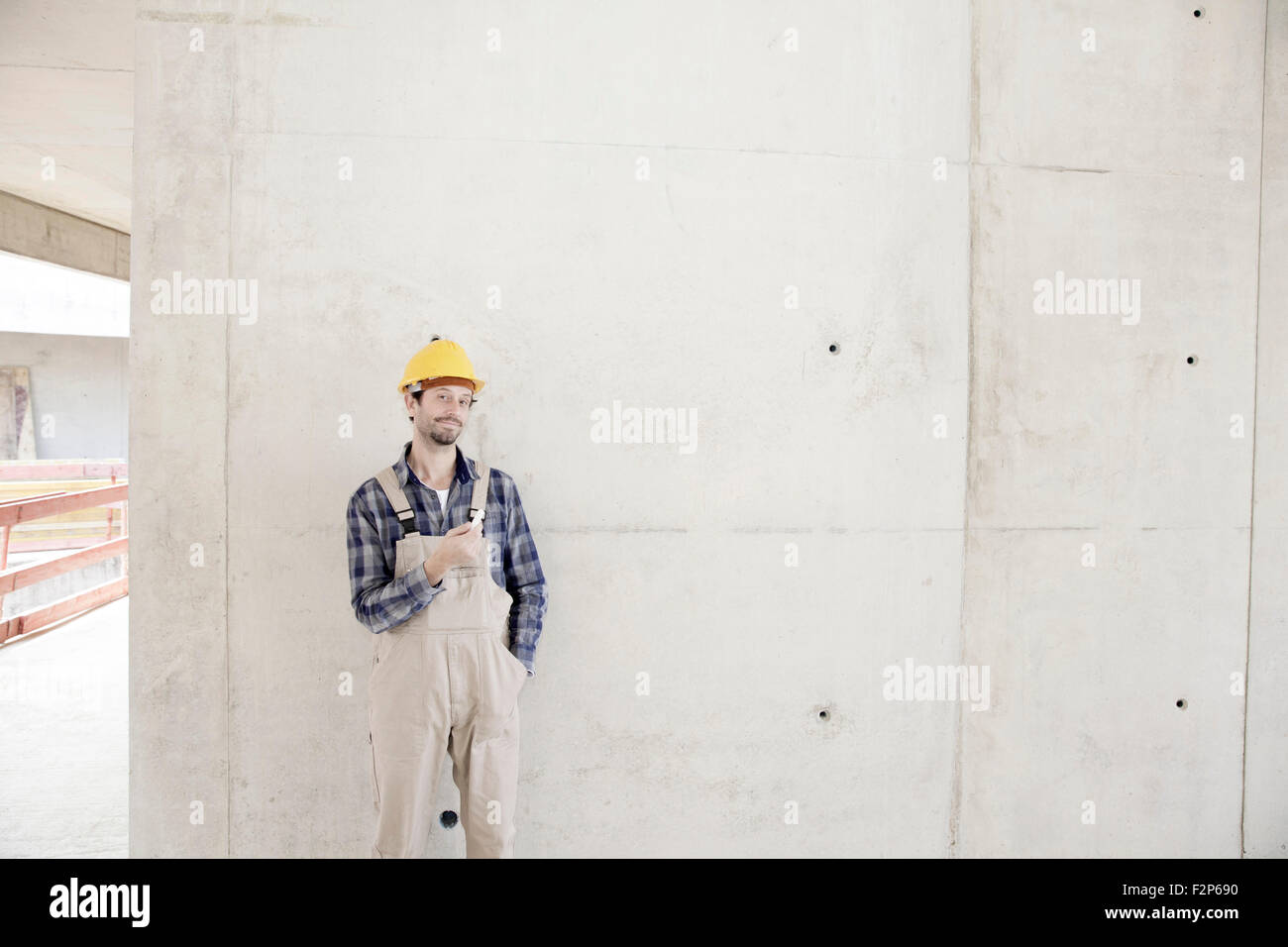 Mann mit Schutzhelm auf Baustelle in Betonwand Stockfoto