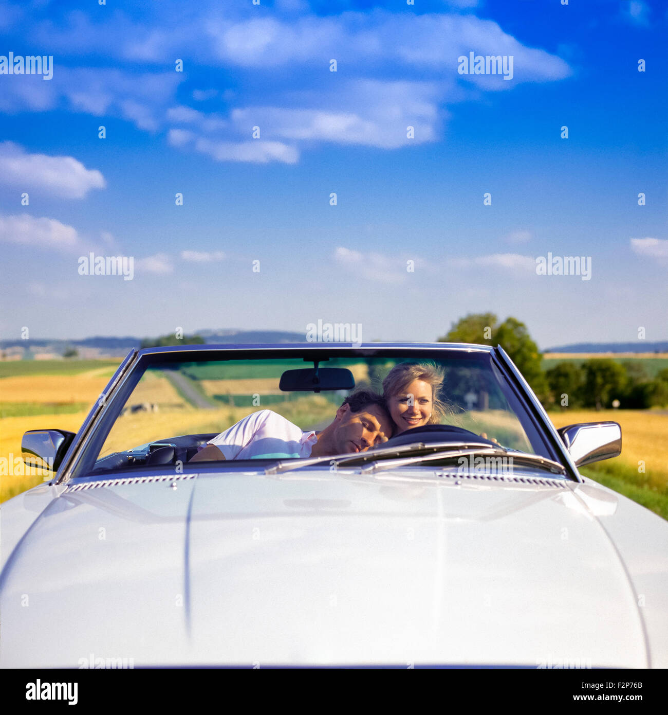 Mann, der auf der Schulter der weiblichen Fahrerin beim Fahren eines Mercedes-Cabrios auf Landstraßen, im Elsass, in Frankreich und in Europa schlagt Stockfoto