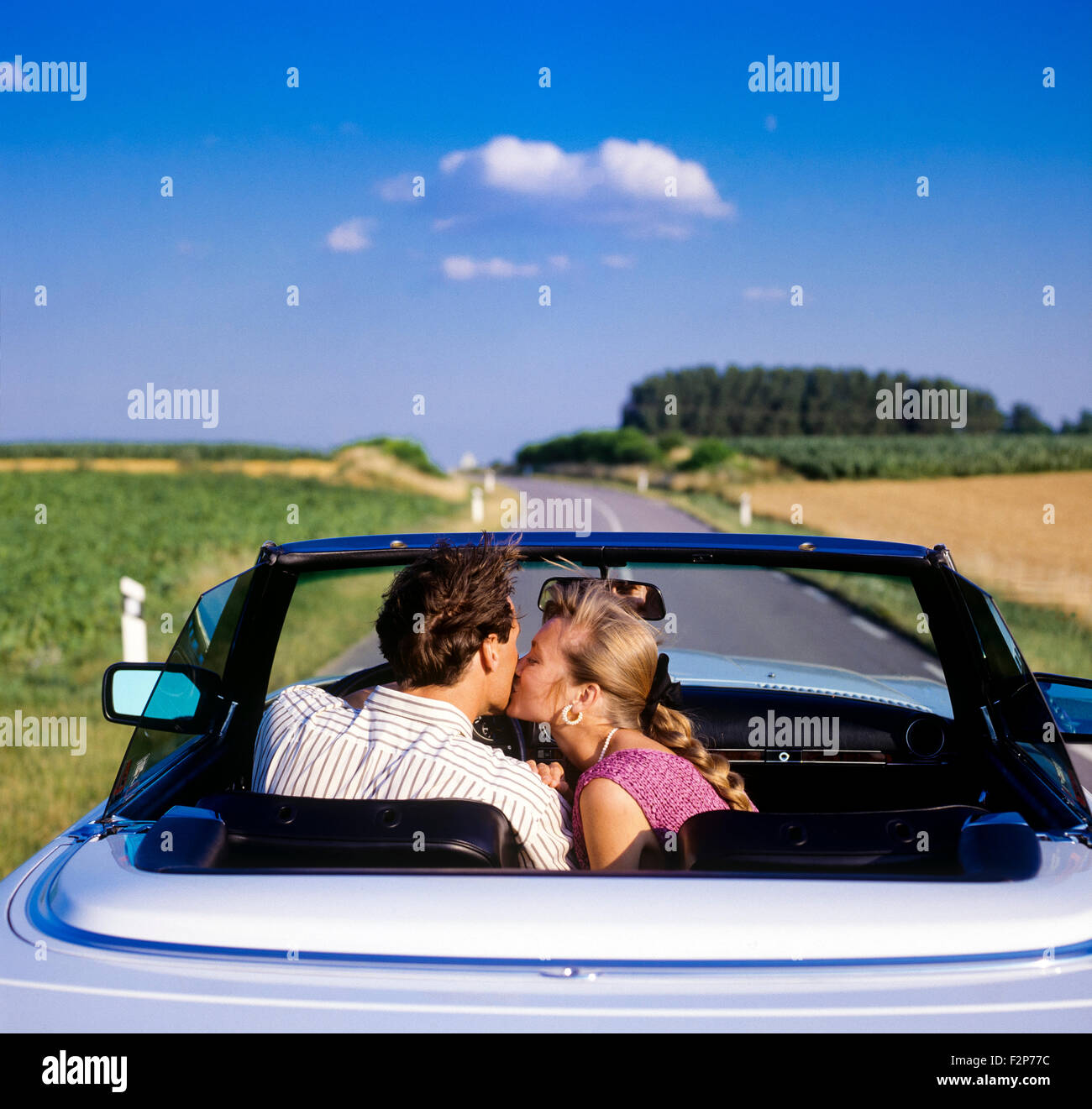 Ansicht der Rückseite Frau küssen den Fahrer während der Fahrt in einem Mercedes cabrio Auto auf Landstraße, Elsass, Frankreich, Europa Stockfoto