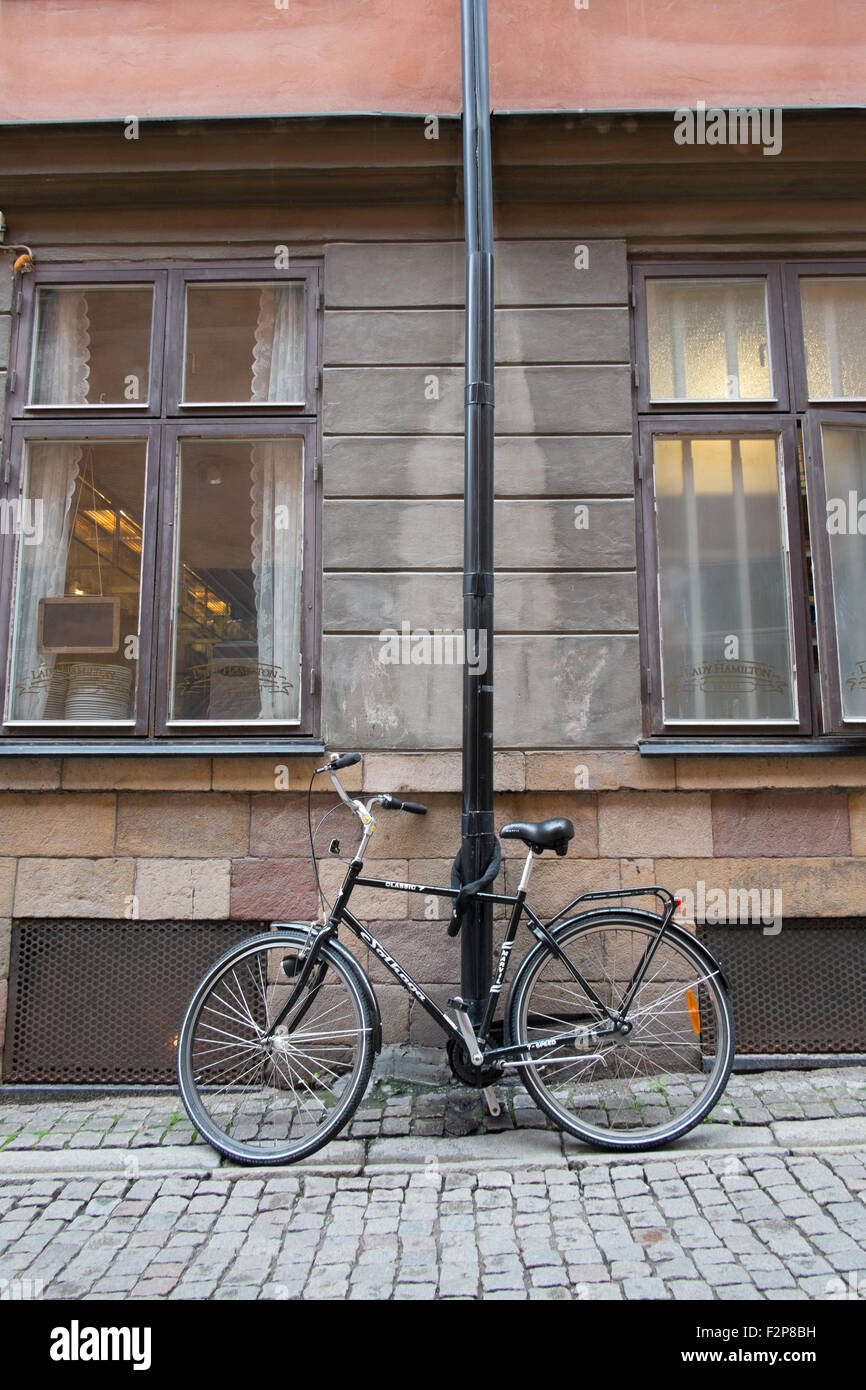 Schwarzes Fahrrad angekettet an einen Laternenpfahl außerhalb ein altes steinernes Gebäude in der Södermalm in Stockholm Stockfoto