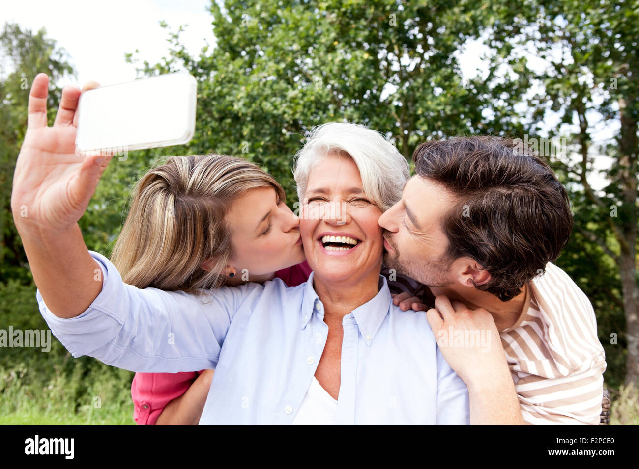 Glückliche Mutter mit erwachsenen Kindern, die Handy-Aufnahme im freien Stockfoto